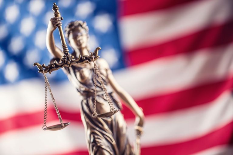 Lady Justice statue in front of United States of America flag.