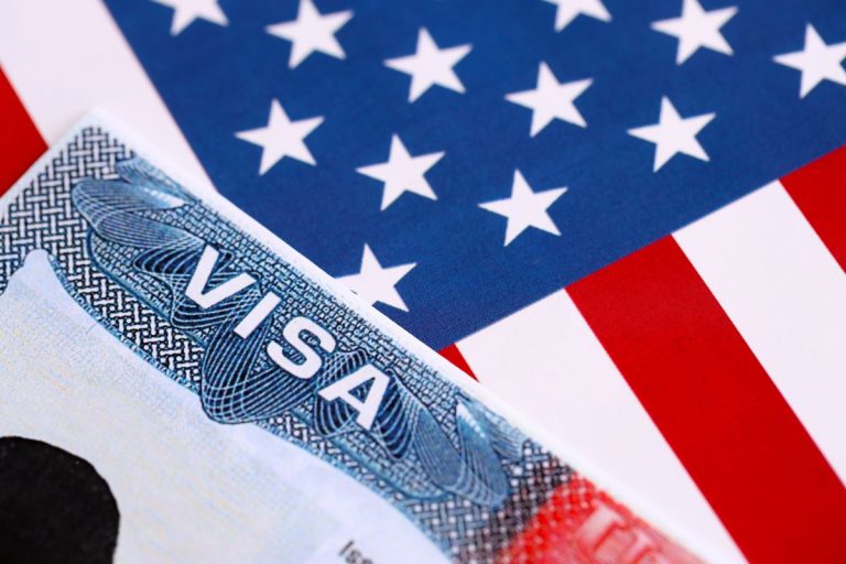 Close up of a United States visa document partially covering an American flag.