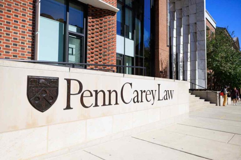 Penn Carey Law building at the University of Pennsylvania with a stone sign reading “Penn Carey Law” outside the modern campus entrance.