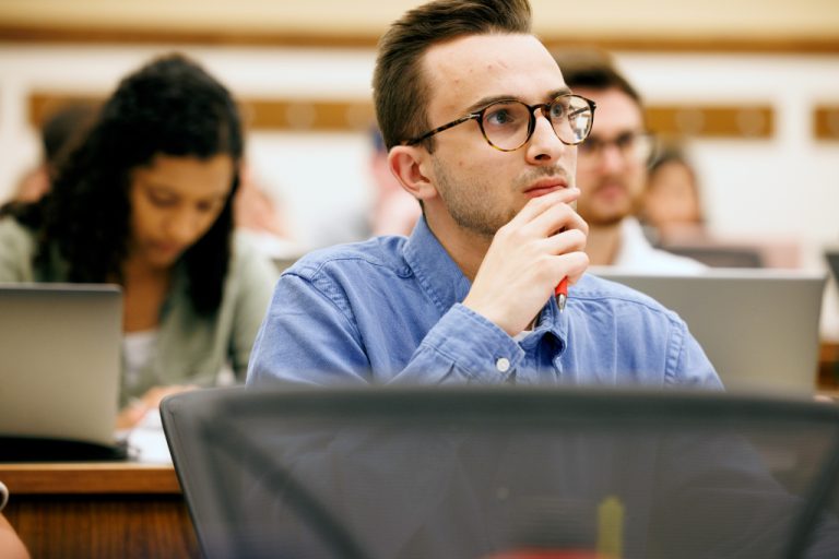 Law student listening attentively during a lecture in a DePaul University College of Law classroom. Photo courtesy of “DePaul University College of Law.”