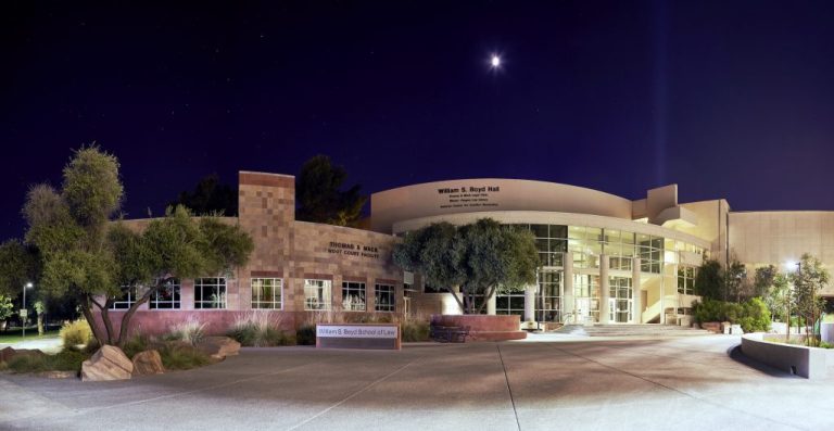 William S. Boyd School of Law building at UNLV illuminated at night with a curved glass entrance and trees surrounding the courtyard.