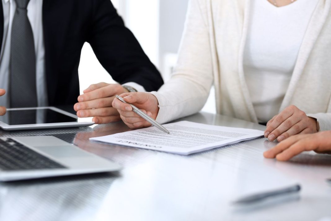 hands of people working at a table reviewing contract