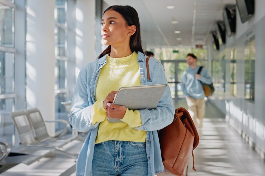girl holding a planner and carrying a tote bag in a school hallway