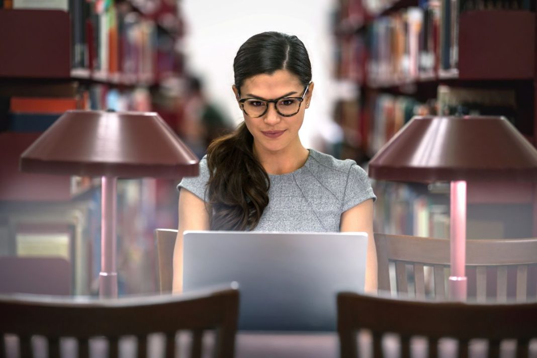 woman looking at a laptop screen in a library
