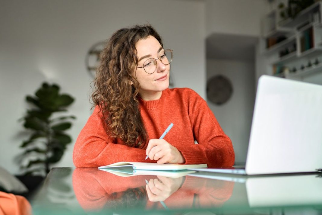 young lady looking at laptop taking notes