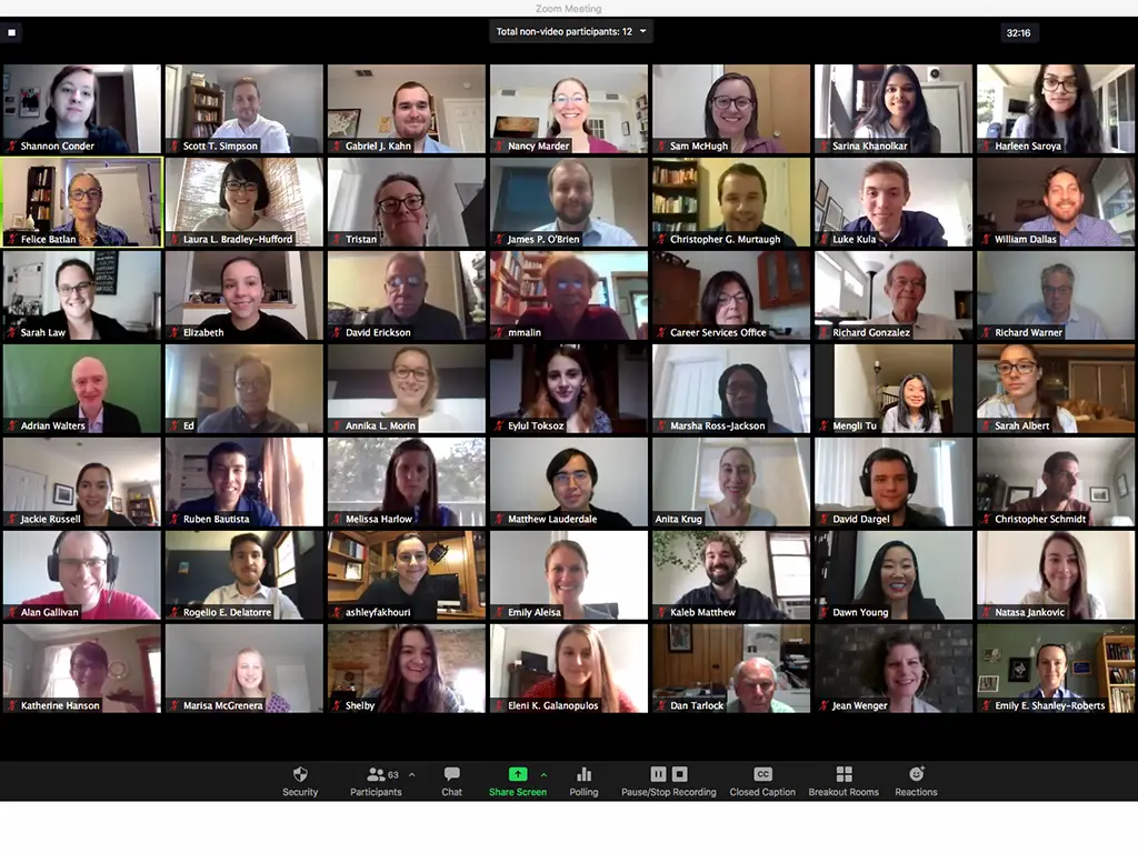 Screenshot of a large Zoom meeting with dozens of participants displayed in a grid of video tiles, showing people attending a virtual class or meeting from their homes.