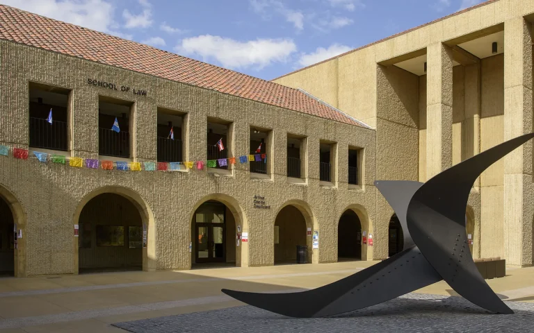 Courtyard of a law school building with arched walkways and a large abstract metal sculpture in the foreground.