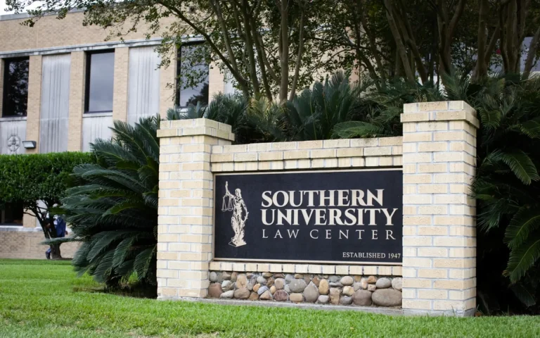Sign for Southern University Law Center displayed on a brick monument surrounded by greenery on the university campus.