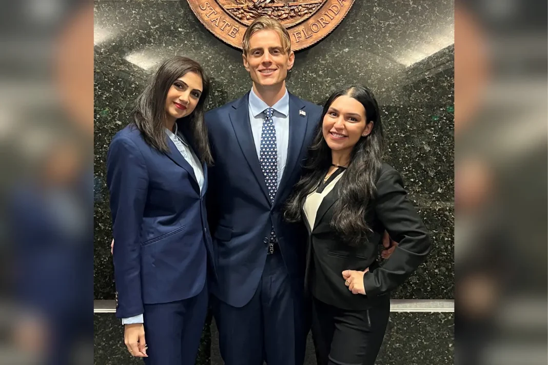 Gabriella Logiudice, Safa Kudia and Colby Weron standing together in professional attire in front of a wall with the State of Florida seal, posing for a photo in a formal setting.