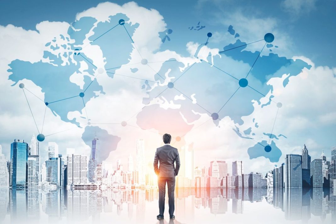 man standing in front of graphic overlay on the world and a skyline of buildings