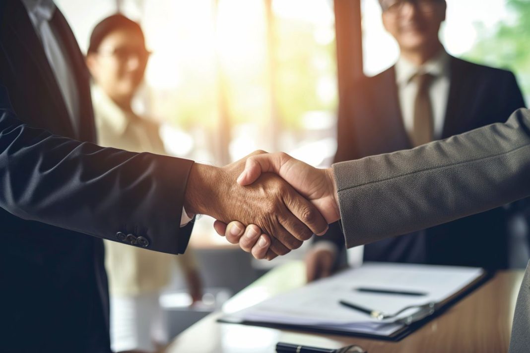 handshake over paperwork on a conference table