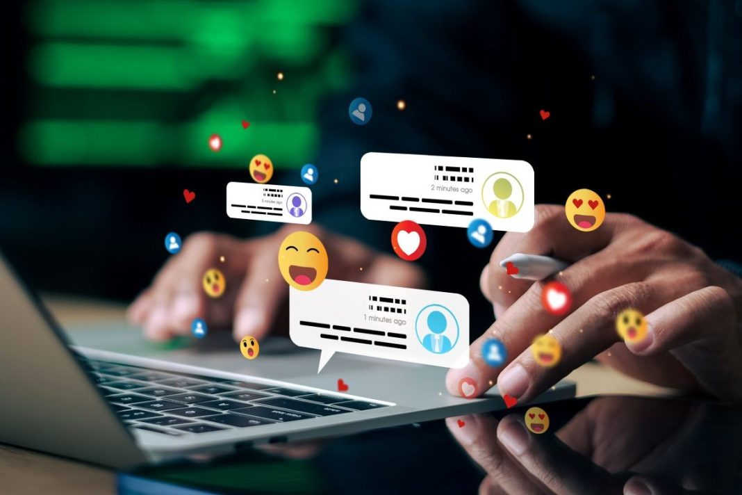 hands on a laptop with emojis of being on social media