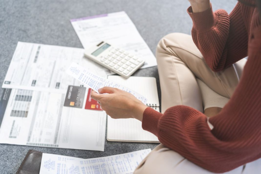 lady sitting on floor in front of bills with a calculator