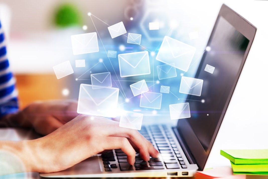 hand on laptop with email emojis floating above keyboard