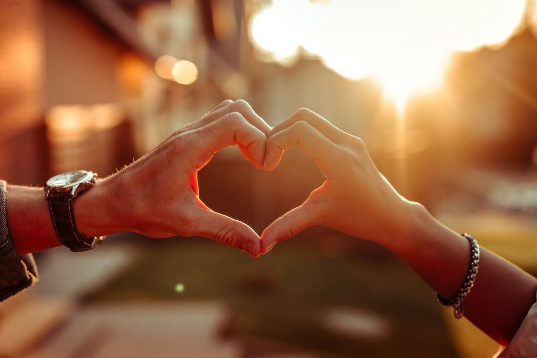 male and female hand form a heart sign