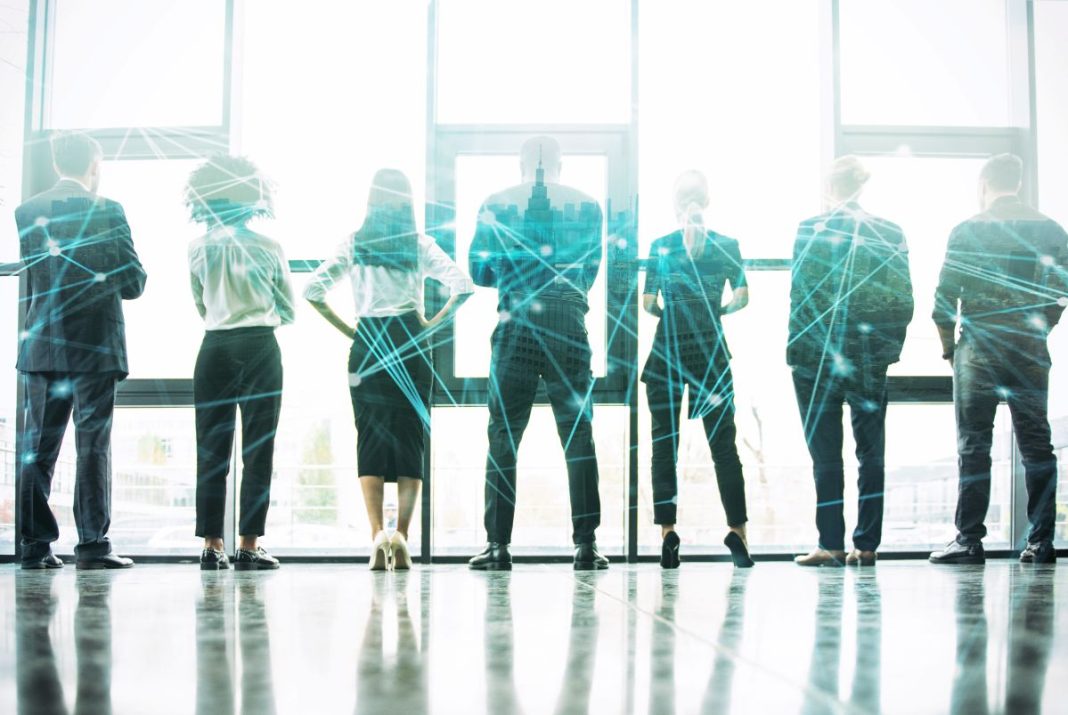 professionals standing in front of office window with graphic overlay of networking