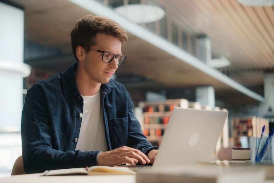 male sitting a desk in front of a laptop
