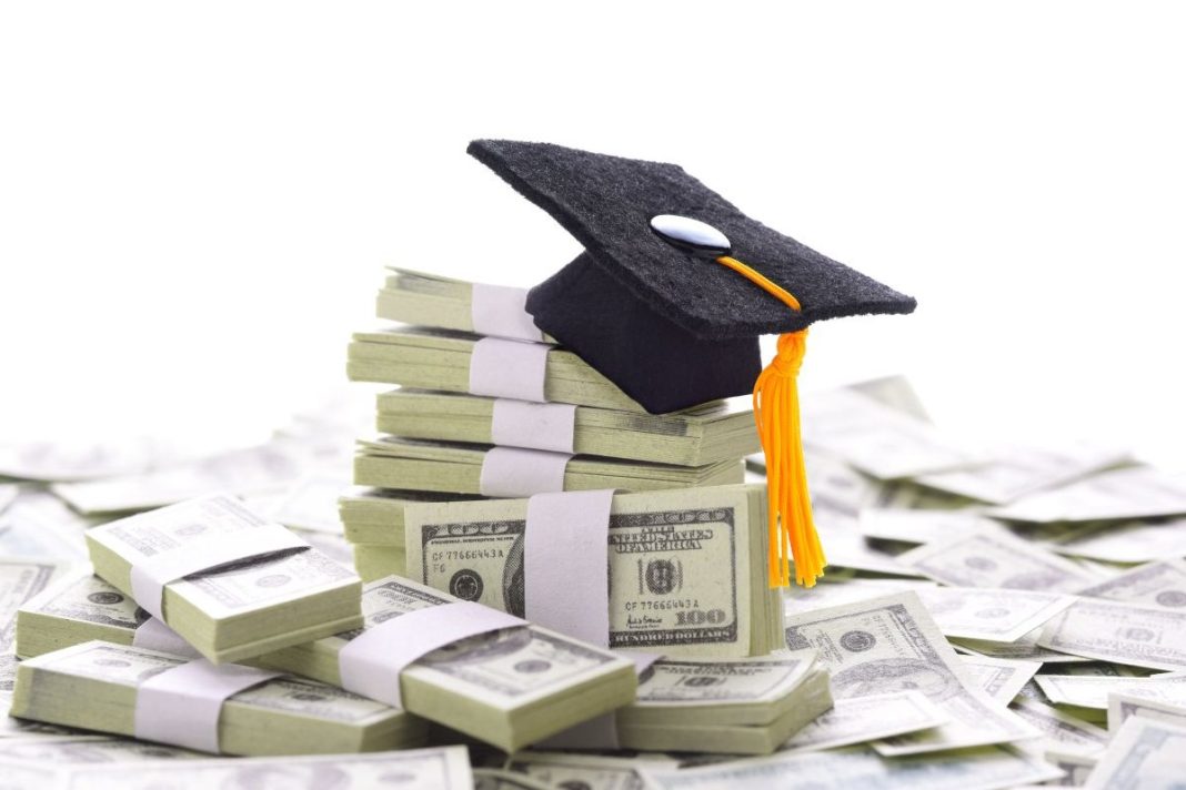 graduate cap on top of a pile of money